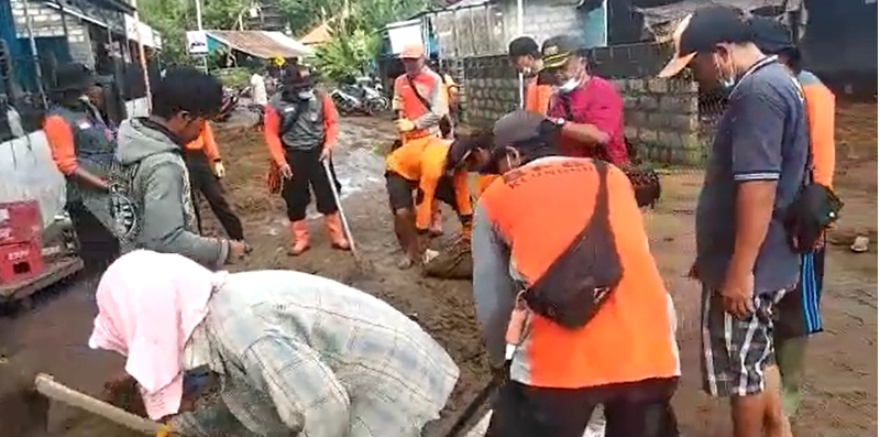 Petugas dan warga membersihkan lumpur dan material sampah pascabanjir bandang di Kabupaten Klungkung, Senin (13/12/2021). (Admin BNPB)