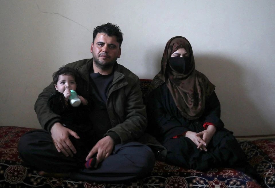 Hamid Safi, sopir taksi berusia 29 tahun yang menemukan bayi Sohail Ahmadi di bandara, menggendong Sohail saat berpose bersama istrinya Farima Safi di rumahnya di Kabul, Afghanistan, 7 Januari 2022