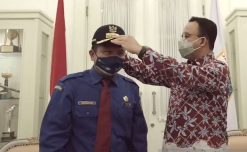 Gubernur DKI Jakarta Anies Baswedan (kanan) menyematkan topi kepada Khaerun, sopir bus yang menyelamatkan seorang wanita hendak bunuh diri di Jakarta, Jumat (28/1/2022)