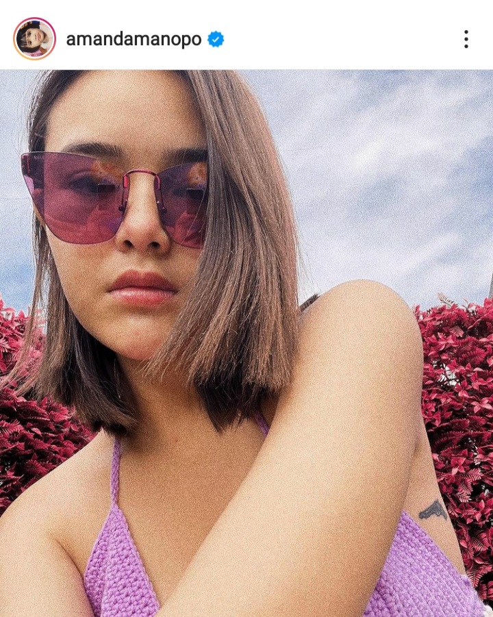 Amanda Manopo tampak anggun mengenakan kaca mata hitam dan baju atasan sedikit terbuka berwarna ungu.