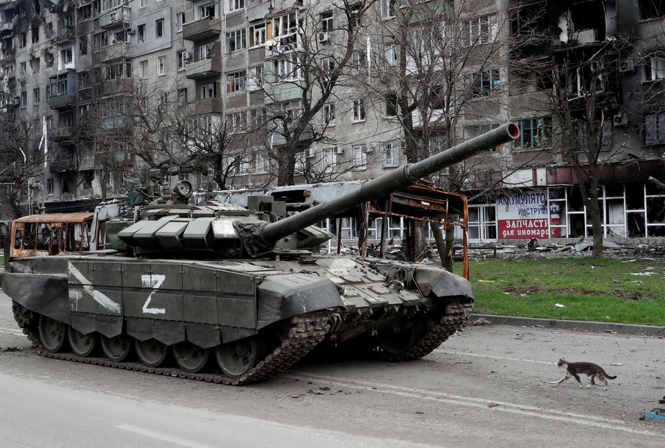 Seekor kucing berjalan di samping tank pasukan pro-Rusia di depan sebuah gedung apartemen yang rusak selama konflik Ukraina-Rusia di kota pelabuhan selatan Mariupol