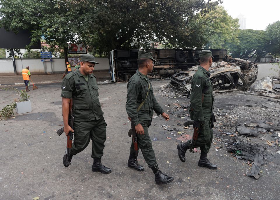 Tentara berjalan melewati kendaraan yang rusak dari pendukung partai yang berkuasa di Sri Lanka setelah mereka dibakar selama bentrokan demonstran pro dan anti-pemerintah di dekat kediaman resmi Perdana Menteri, di tengah krisis ekonomi negara itu, di Kolombo, Sri Lanka, 10 Mei, 2022. 