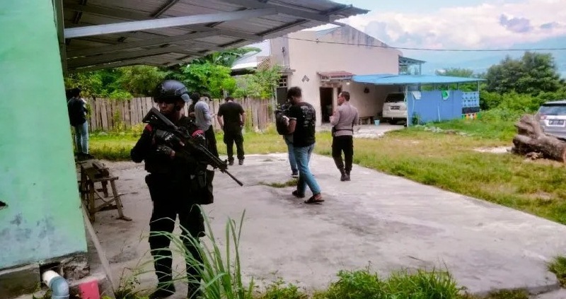 Salah satu anggota Densus 88 bersenjata lengkap berdiri di rumah yang dilakukan penggeledahan oleh polisi di Provinsi Sulawesi Tengah, Kamis (16/3/2023). (Ant)